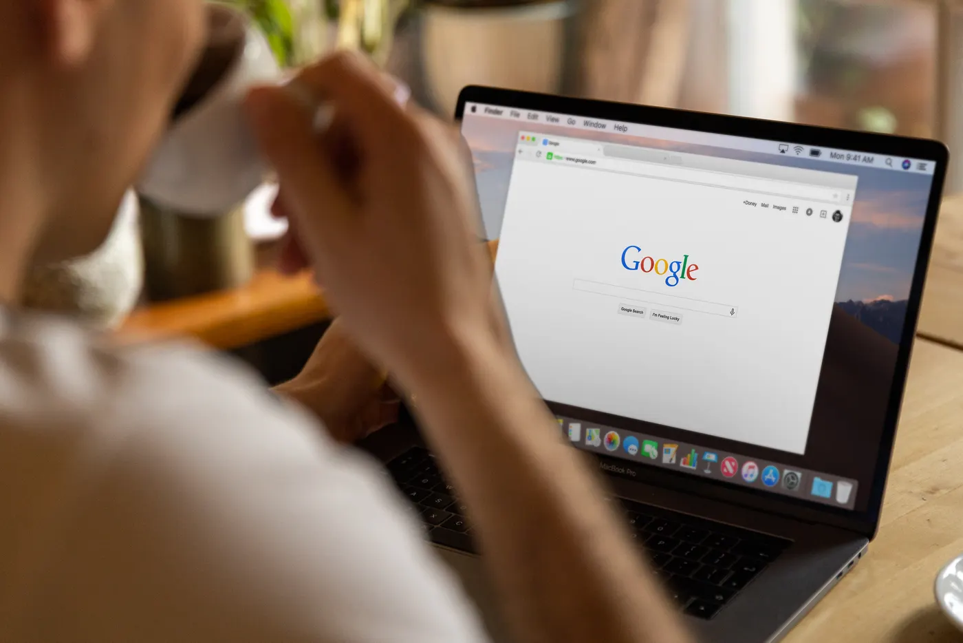 Person drinking coffee while browsing the web on a laptop
