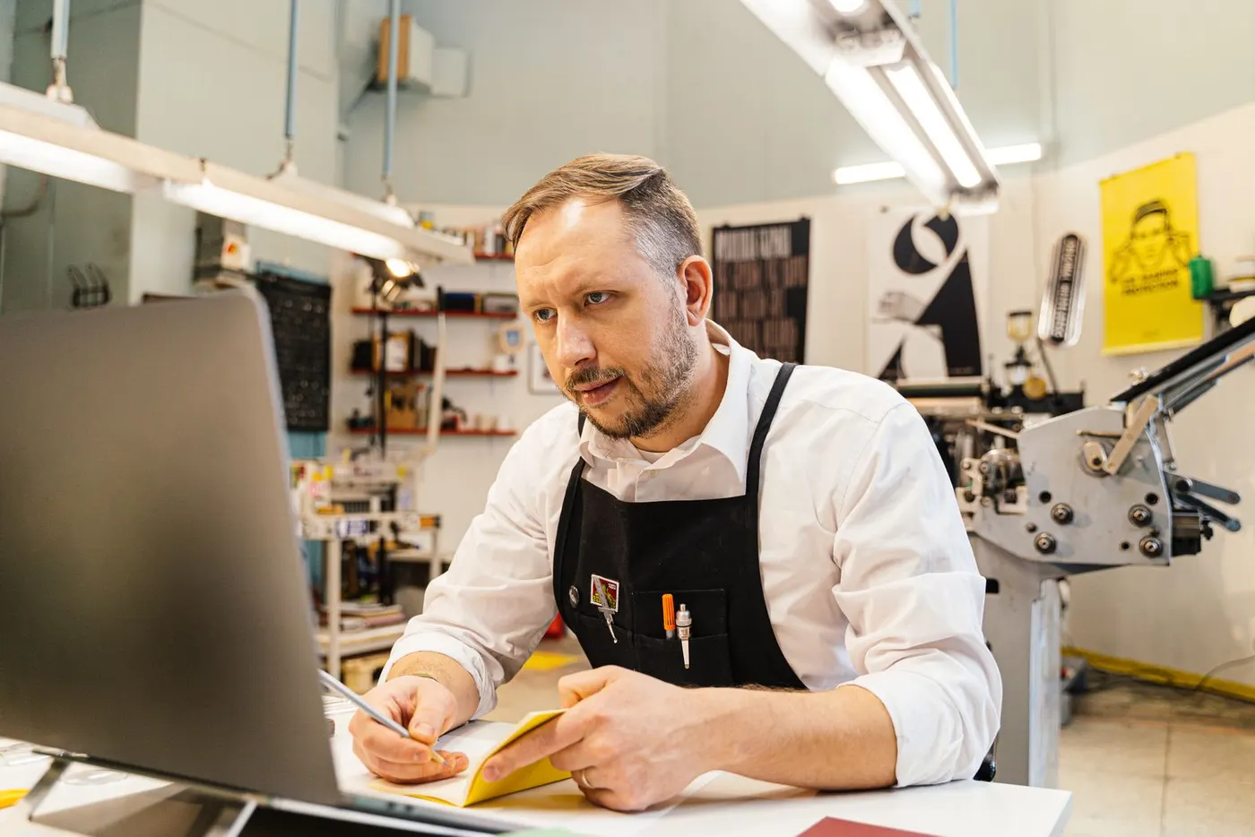 Print shop owner working on a laptop in his workshop